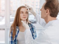 Aged dermatologist touching patient face in the clinic