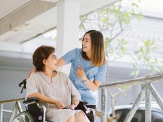 Smiling physiotherapist  taking care of the happy senior patient in wheelchair