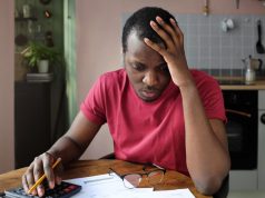 Young anxious worrying african american man looks desperately to bills