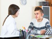 Teenager and doctor at desk in clinic.